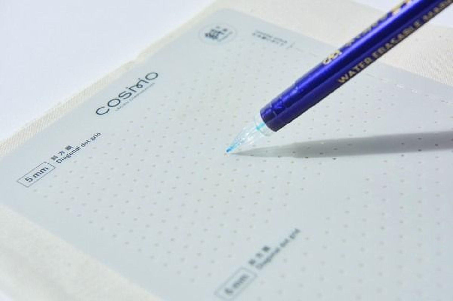 A blue pen is resting on a white surface, with the pen's tip pointing towards the top right corner of the image.