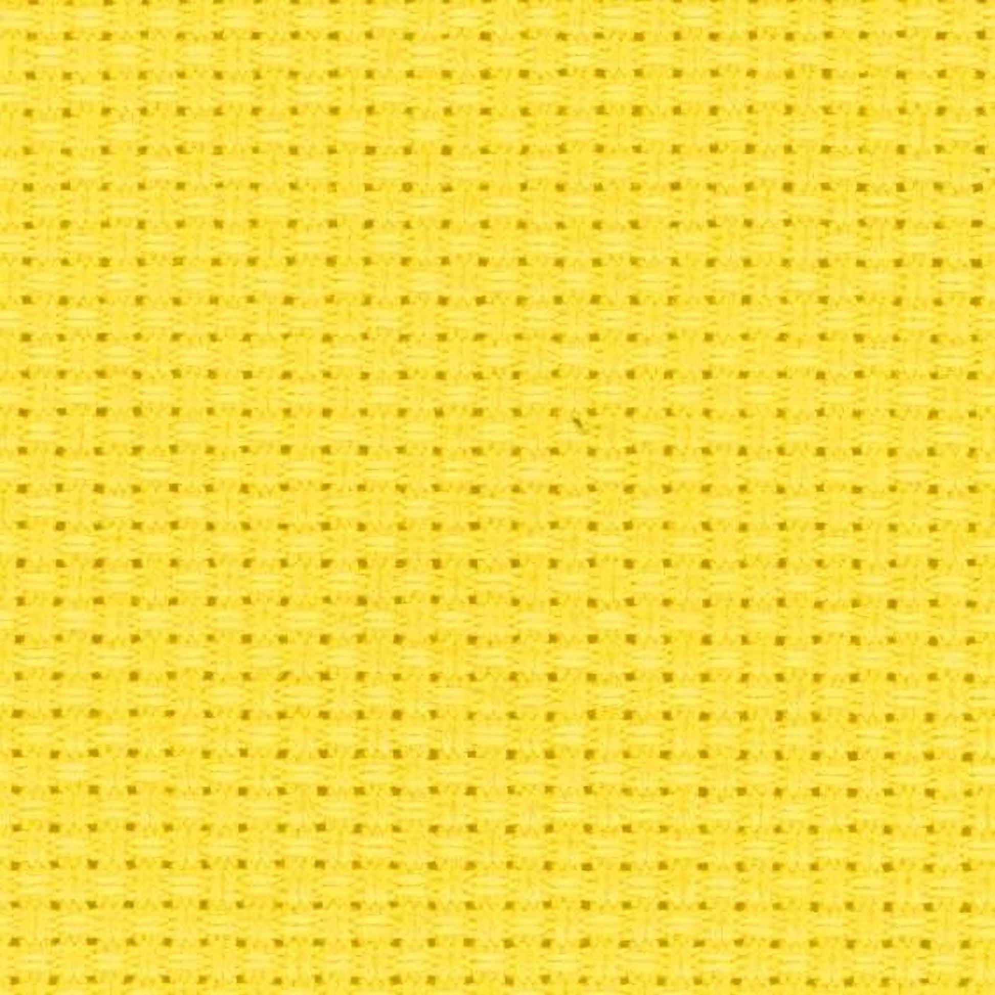 The image is a close-up of a yellow fabric with a grid-like pattern, which appears to be a cross-stitch design.
