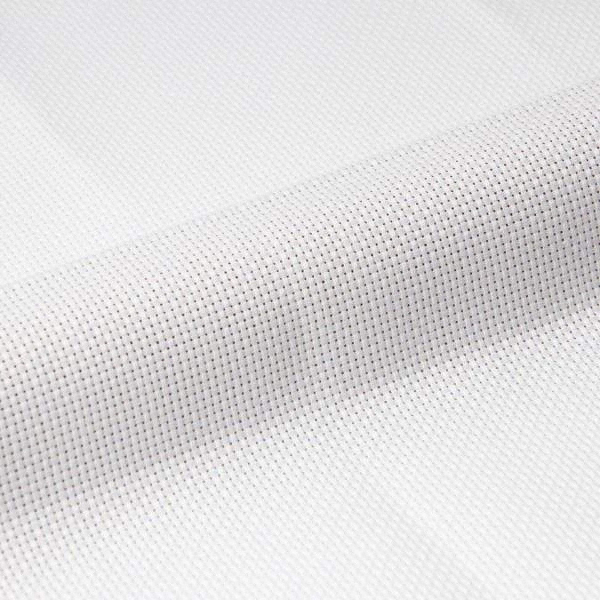 A close-up view of a white fabric with a cross-stitch pattern, featuring small white dots arranged in a grid-like pattern.