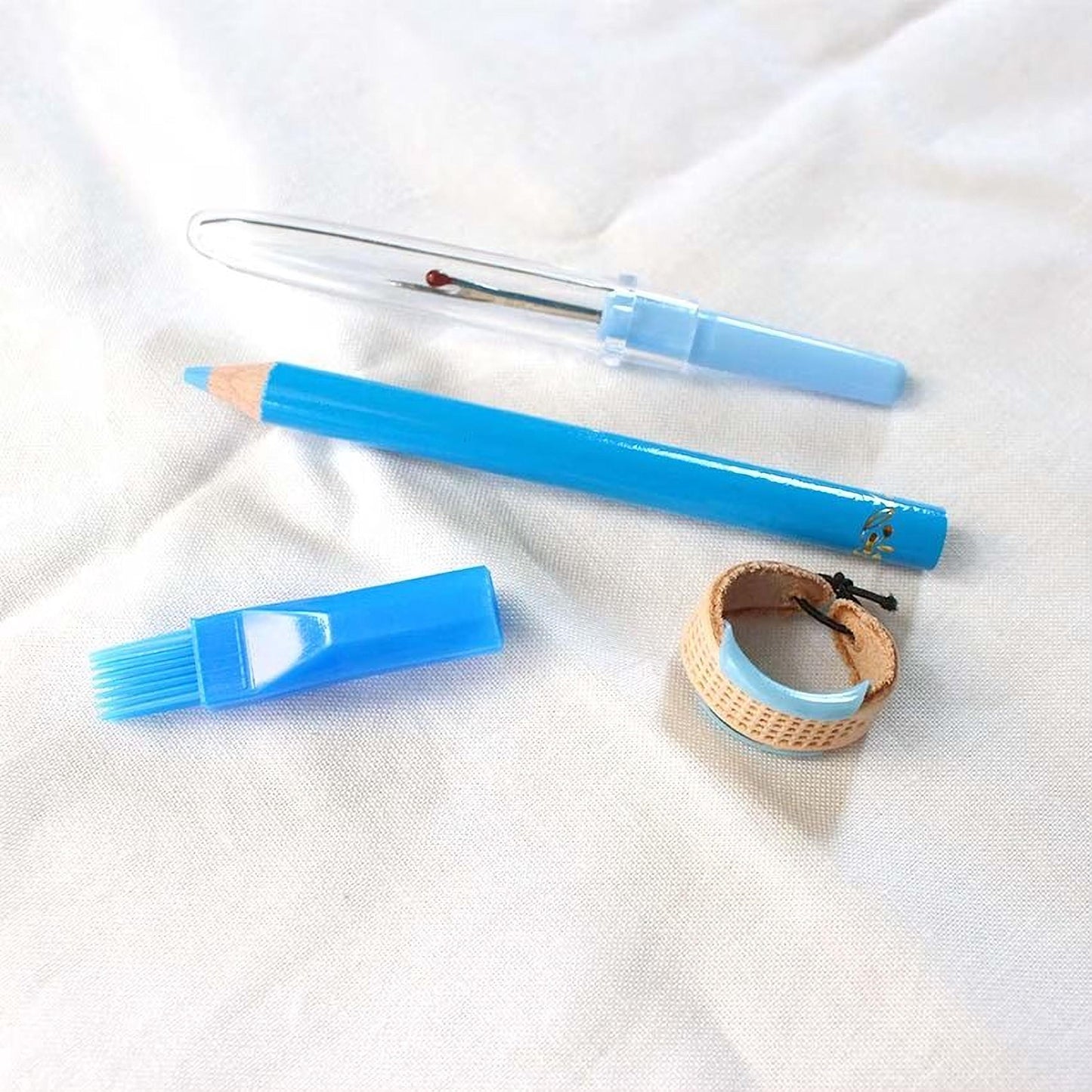 a blue pencil, a blue brush, a blue watch, and a blue ring, all placed on a white cloth.
