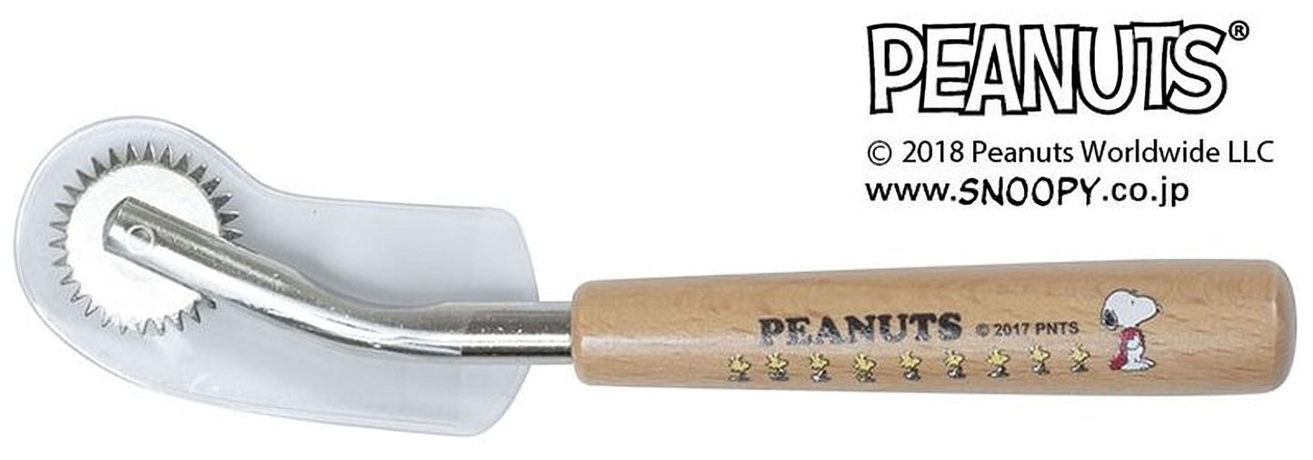 A Peanuts themed rolling pin with a wooden handle and a clear plastic roller guard.