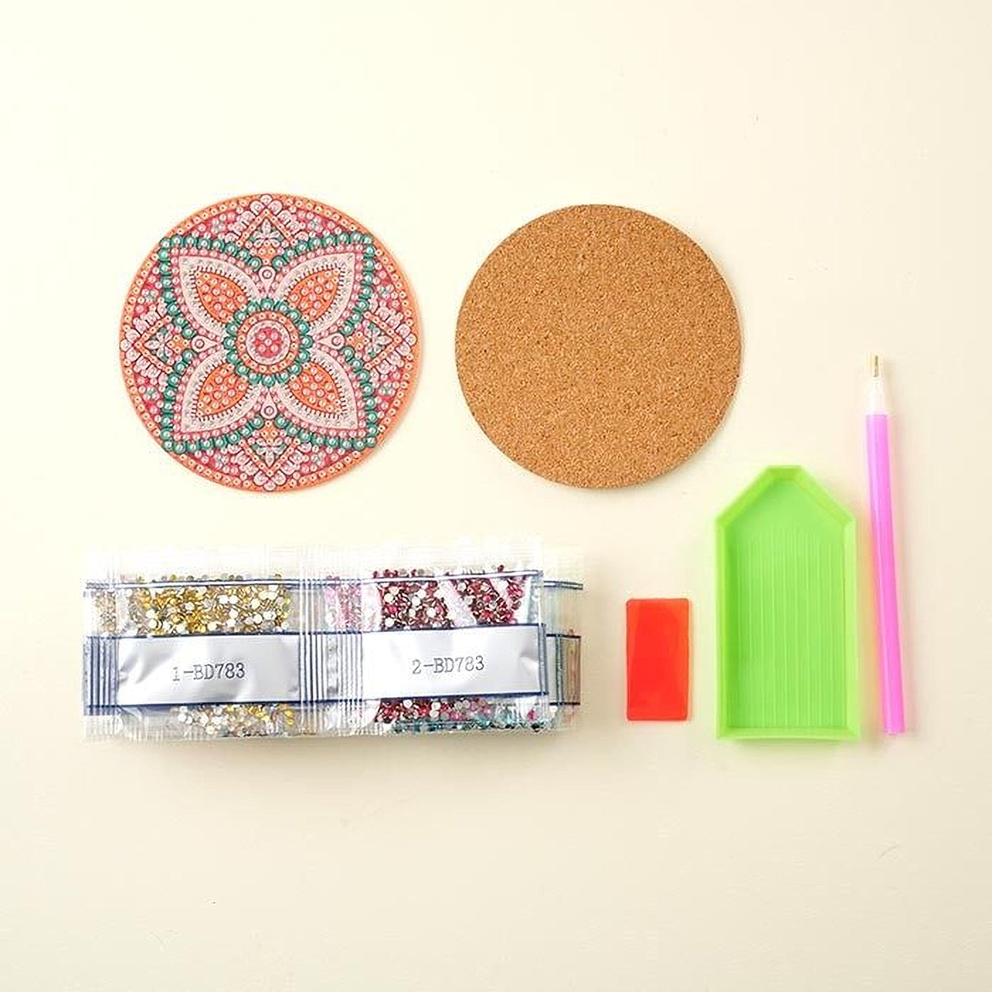 various craft supplies, including a cork coaster, a pen, a small plastic tray, and a package of beads.