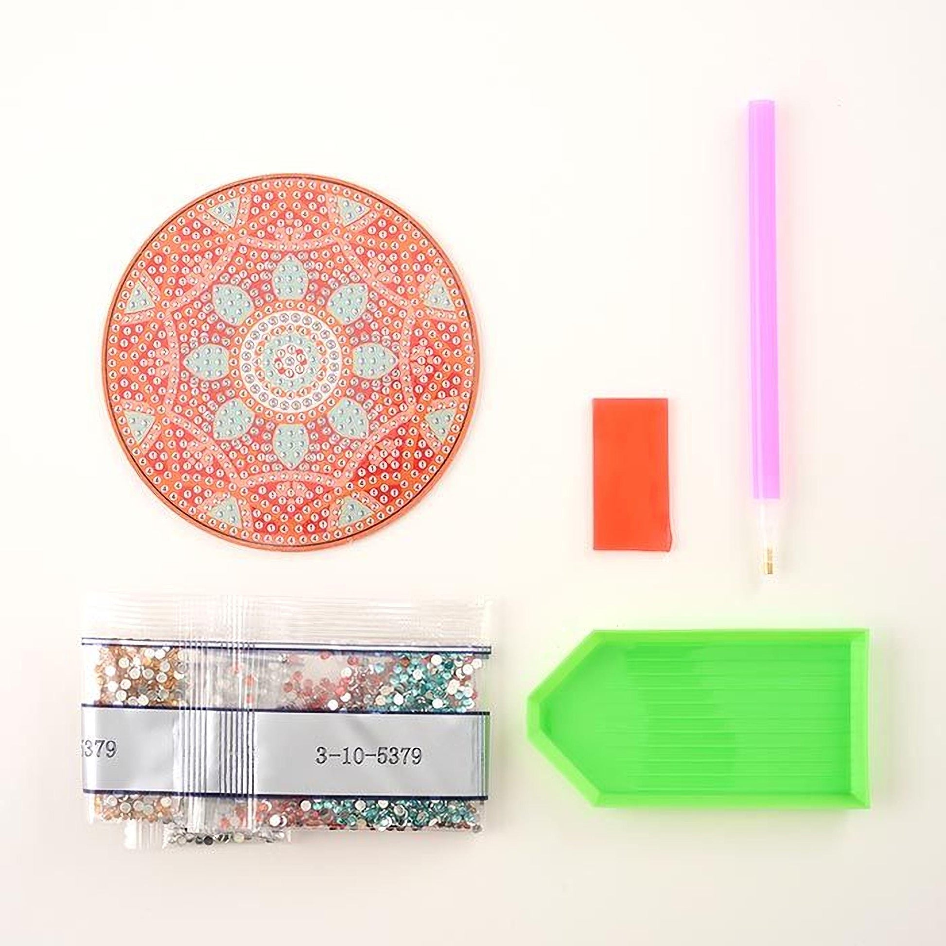 a variety of craft supplies, including a red and orange mandala-patterned coaster, a green and orange plastic tray, a pink and purple pen, a red and orange eraser, and a bag of colorful glitter.