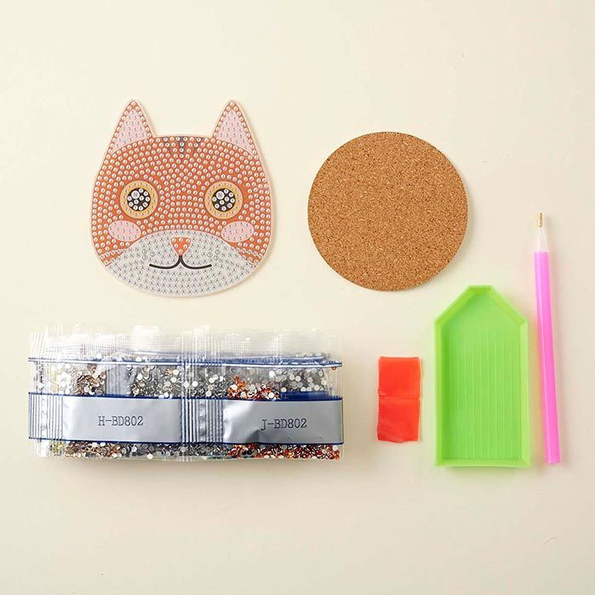 various craft supplies, including a cat-shaped object, a cork coaster, a pen, a small plastic container, and a pair of scissors.