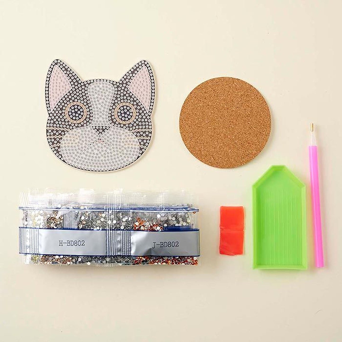 various craft supplies, including a cat-shaped object, a cork coaster, a pen, a small plastic container, and a red and orange object.