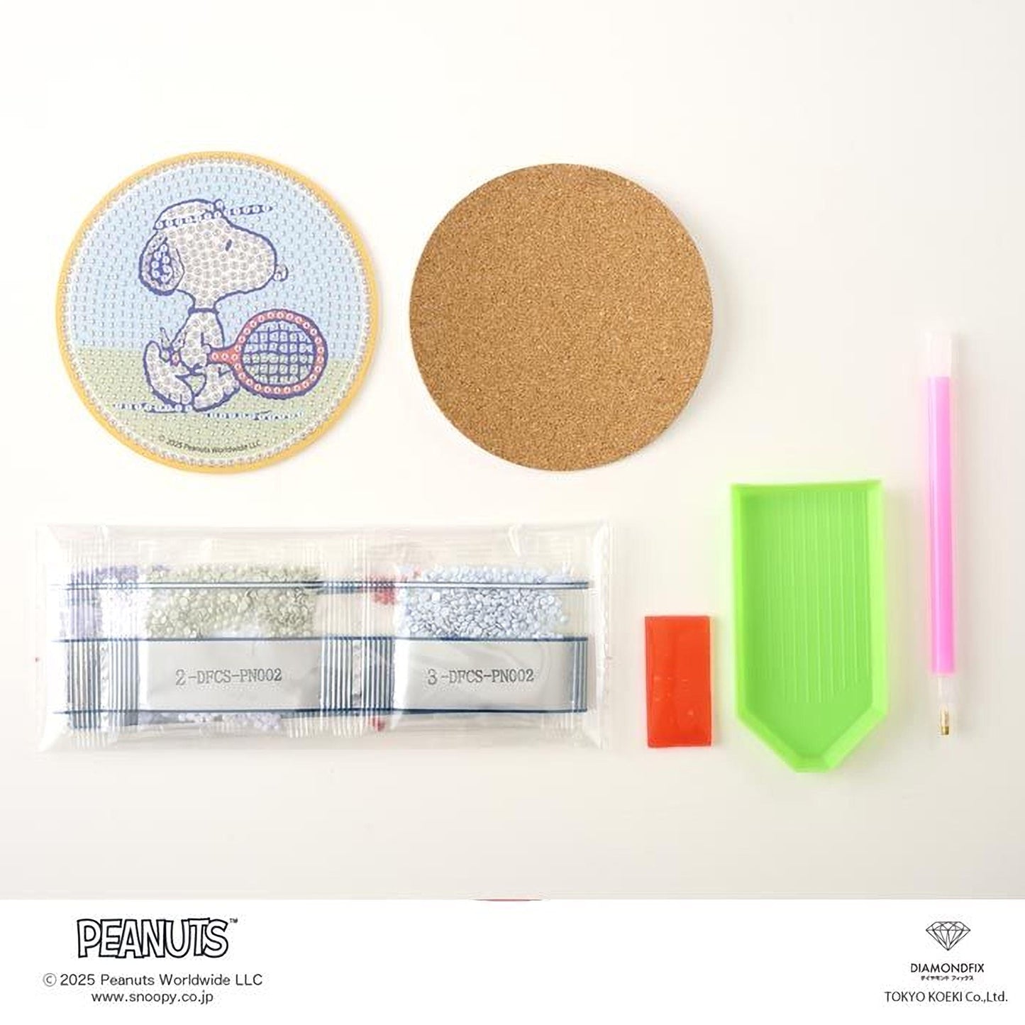 various Peanuts-themed items, including a round coaster with a cartoon image of Peanuts, a cork coaster, a pen, a green plastic tool, and some small items.