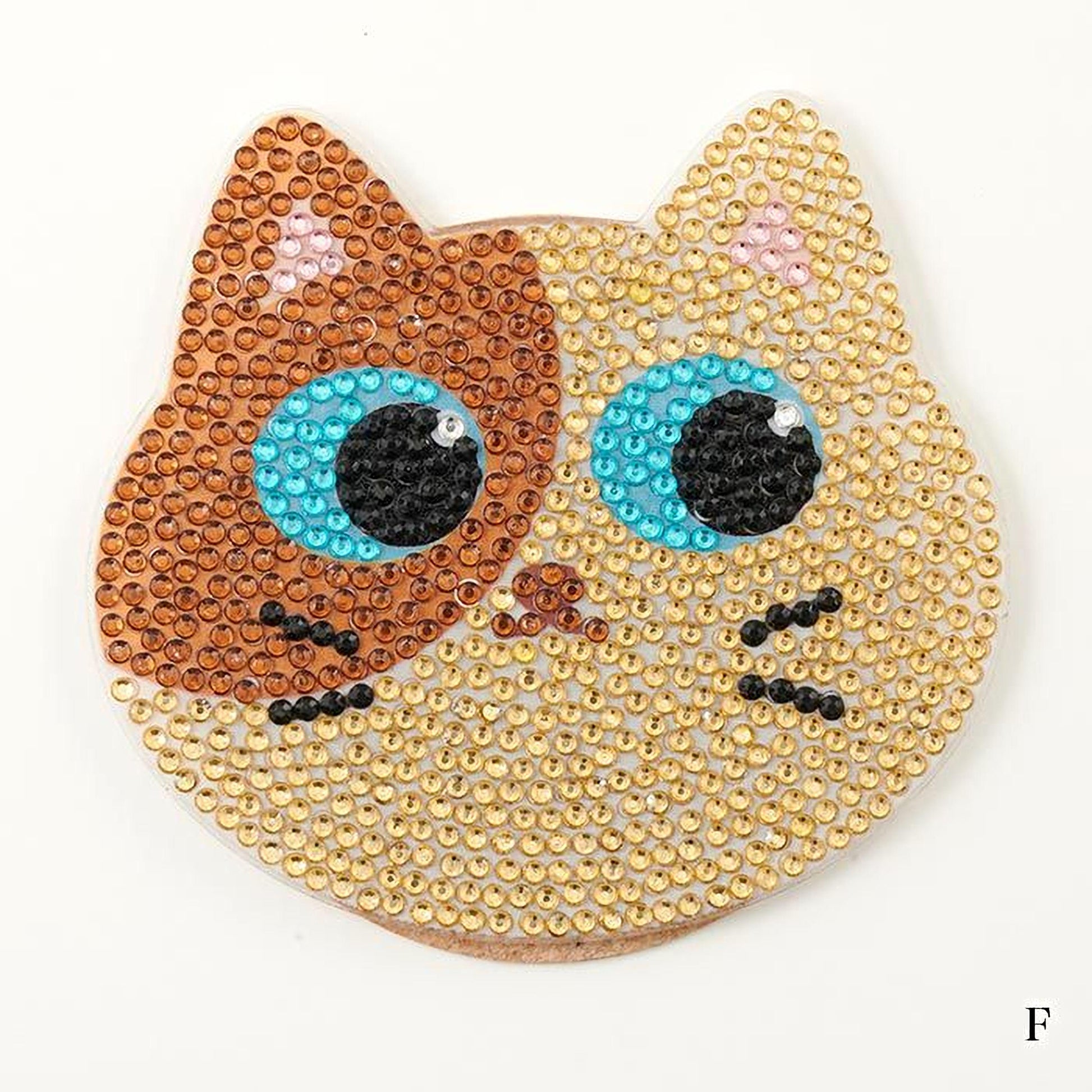 A decorative cat-shaped object made of small, colorful beads or sequins, with large blue eyes and a brown nose.