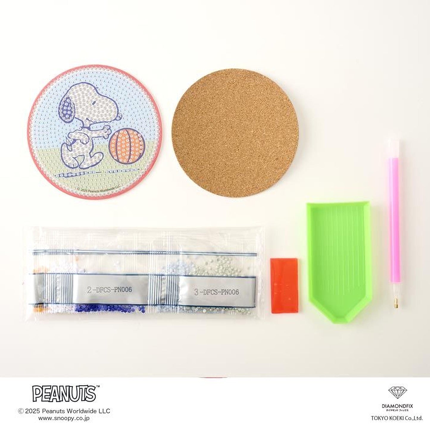 various items related to the Peanuts comic strip, including a round coaster with a cartoon image of Snoopy, a cork coaster, a pen, a magnifying glass, a bag of beads, and a diamond grater.