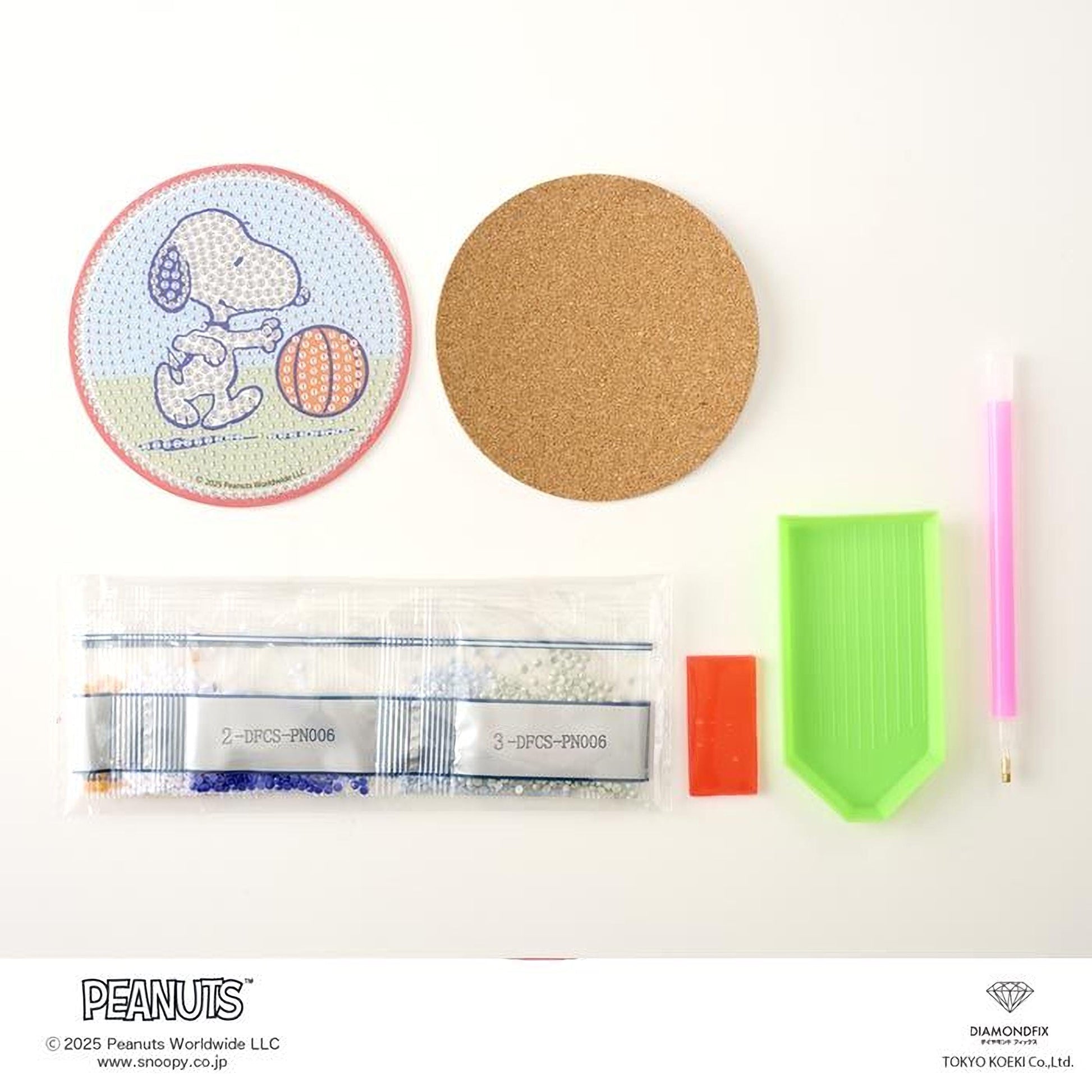 various items related to the Peanuts comic strip, including a round coaster with a cartoon image of Snoopy, a cork coaster, a pen, a magnifying glass, a bag of beads, and a diamond grater.