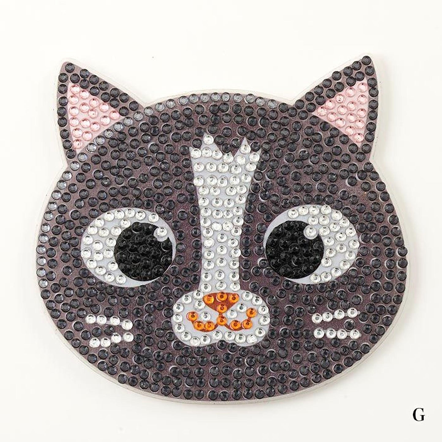 A black and white cat-shaped object made of small beads or sequins, with large eyes and a pink ear.
