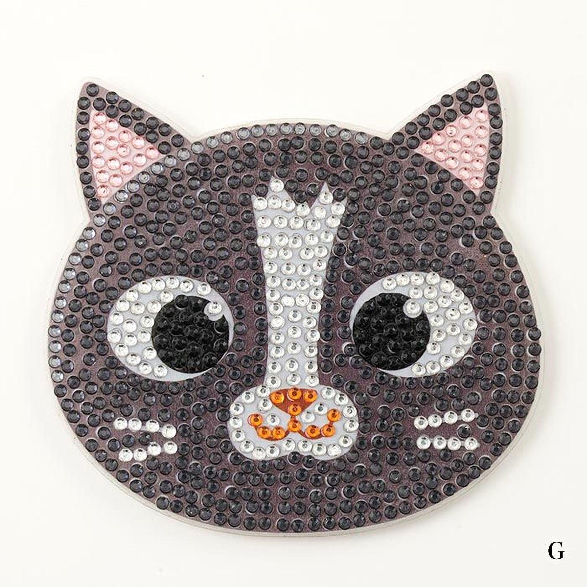 A black and white cat-shaped object made of small beads or sequins, with large eyes and a pink ear.