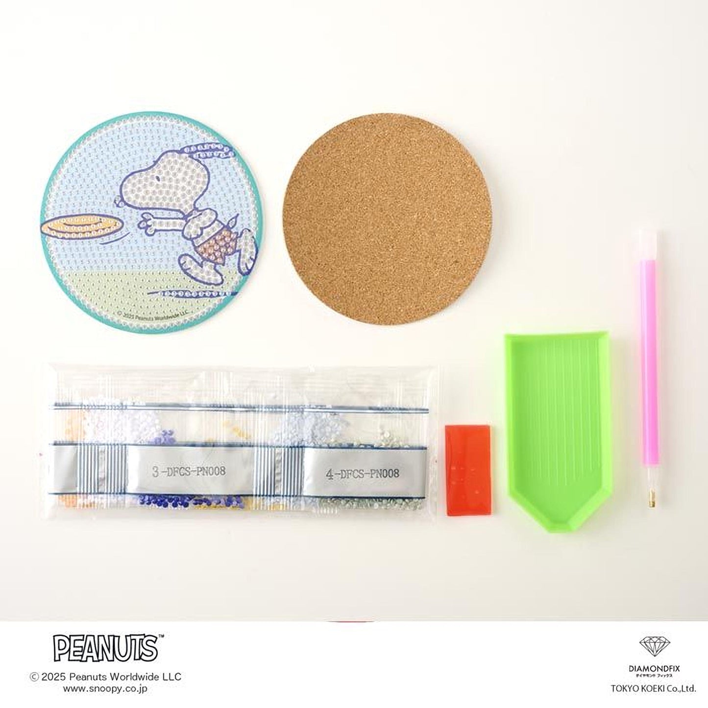 various Peanuts-related items, including a blue and white Peanuts coaster, a cork coaster, a pink pen, a green diamond pick, and a bag of Peanuts-themed beads.