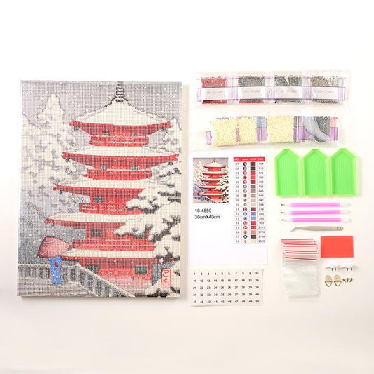 a kit for creating a diamond painting of a red pagoda, along with various tools and materials such as a magnifying glass, scissors, and a calendar.