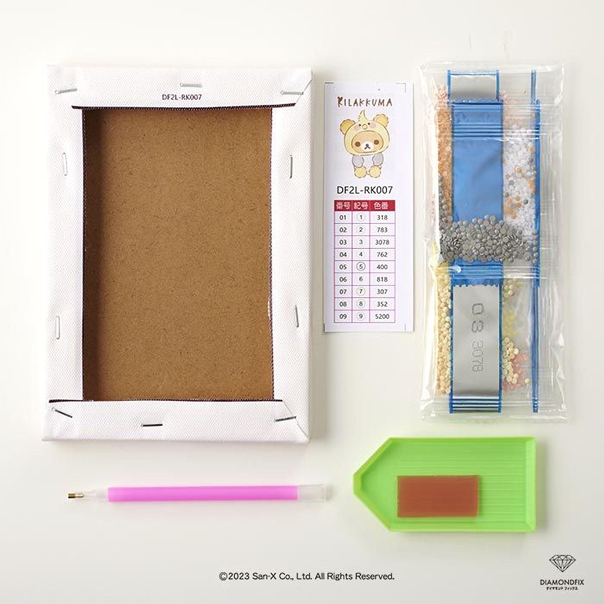 various craft supplies, including a blank white frame, a pink pen, a green diamond wreath, and a bag of diamond dust.