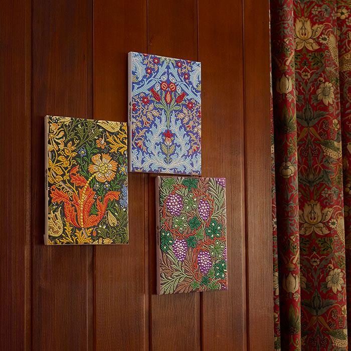 three distinct paintings hanging on a wooden wall.