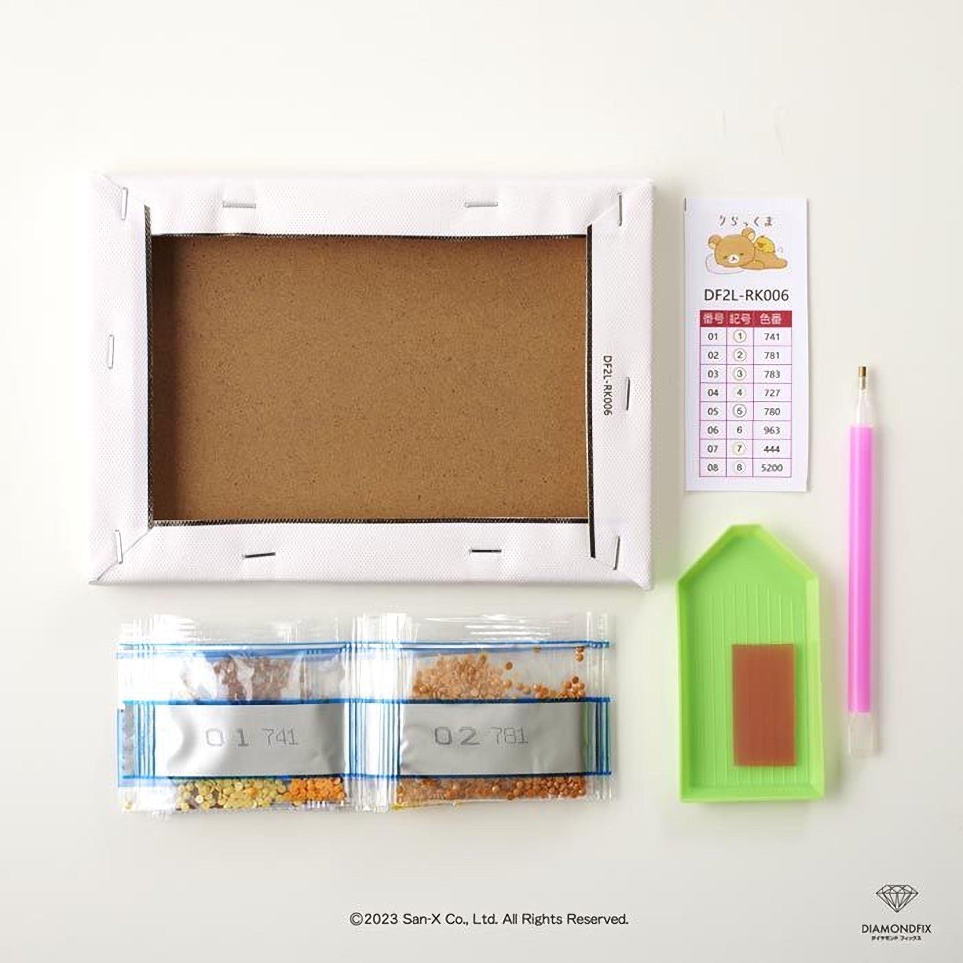 various craft supplies, including a blank canvas frame, a diamond grinder, a bag of craft glitter, and a pen.