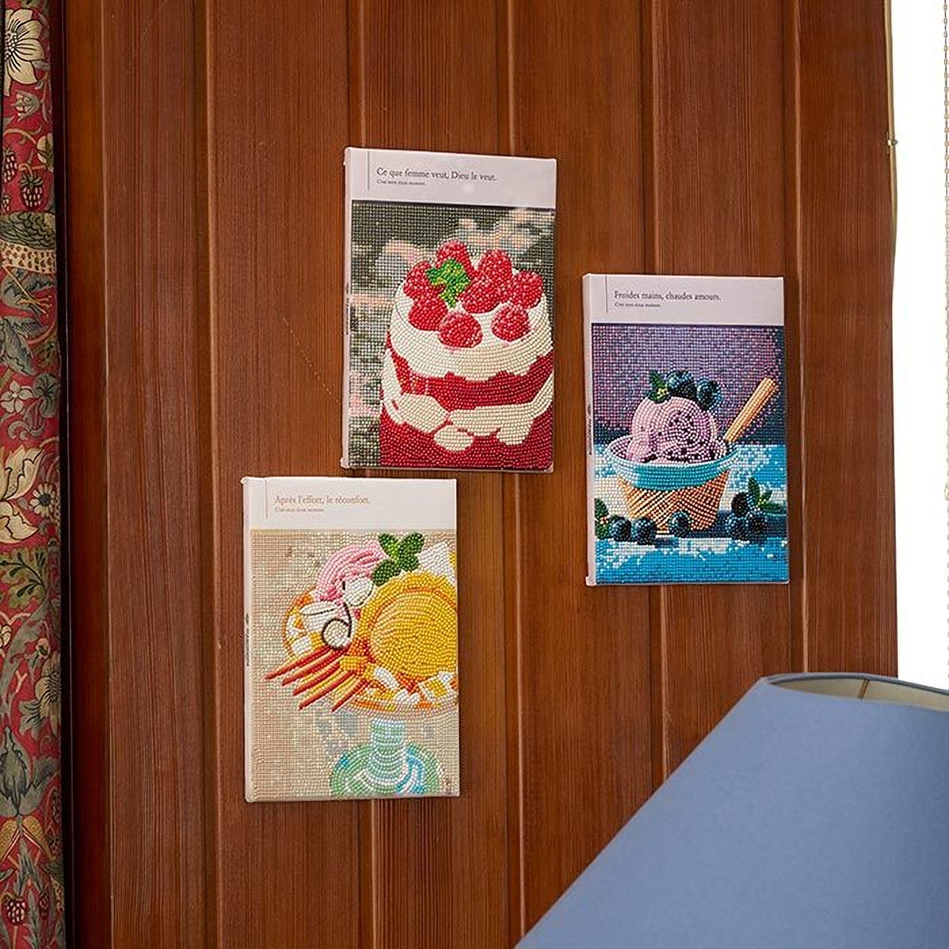 three framed pictures of desserts hanging on a wooden wall.