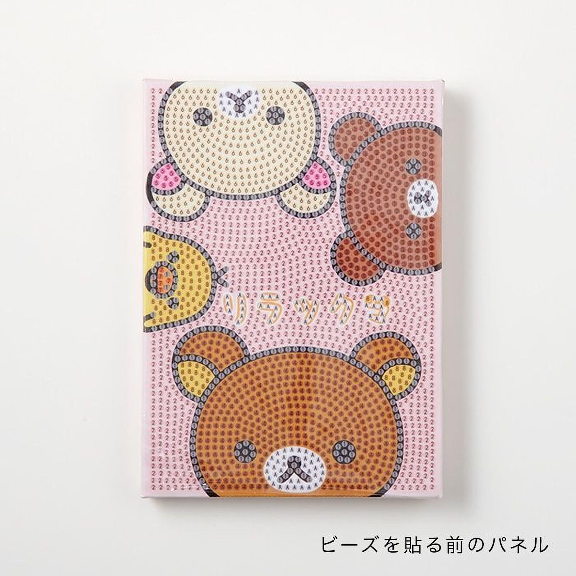 A pink notebook cover with a playful design featuring cartoon bear faces in various colors.