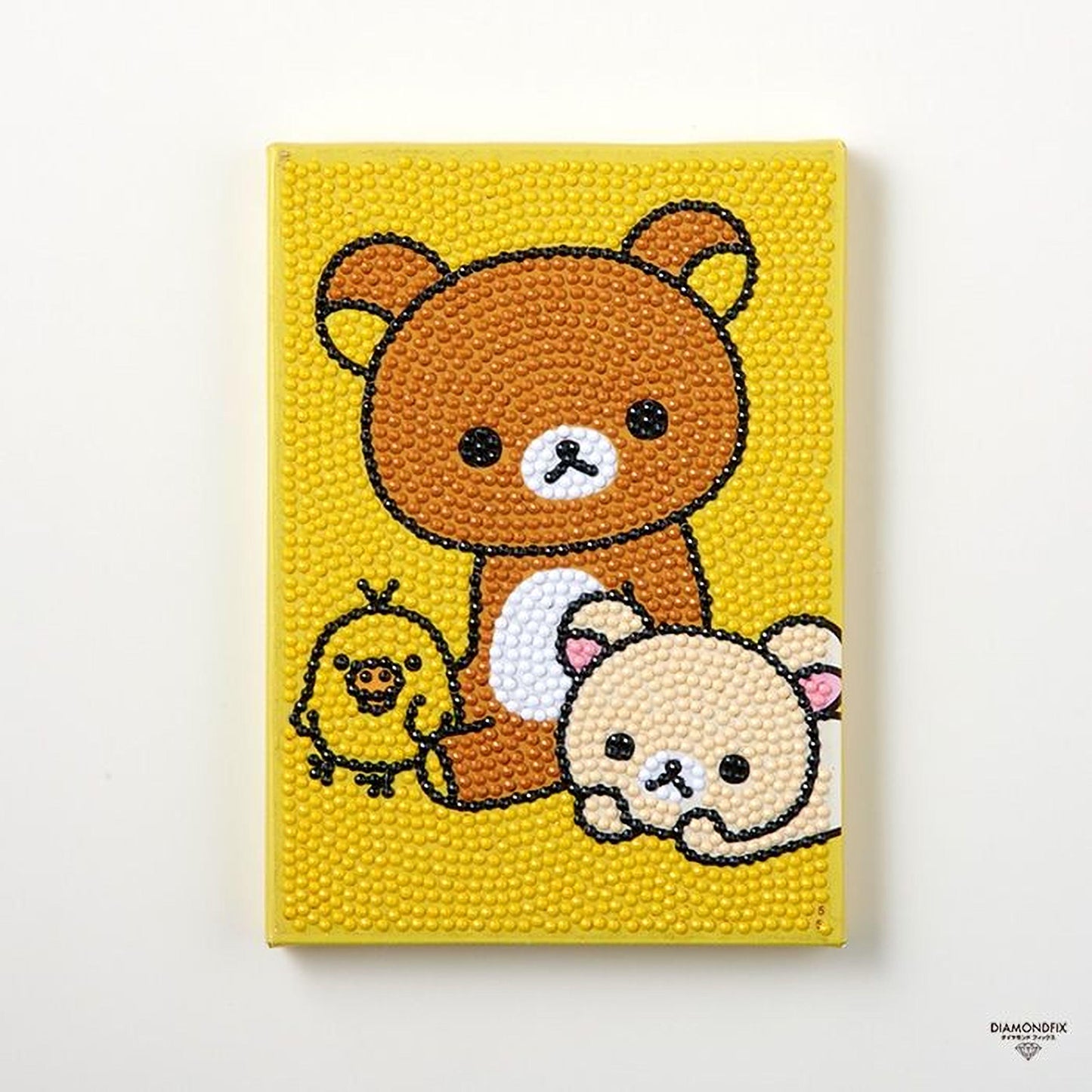 A yellow canvas with a cartoon-style bear and two smaller animals, likely birds, arranged on it.