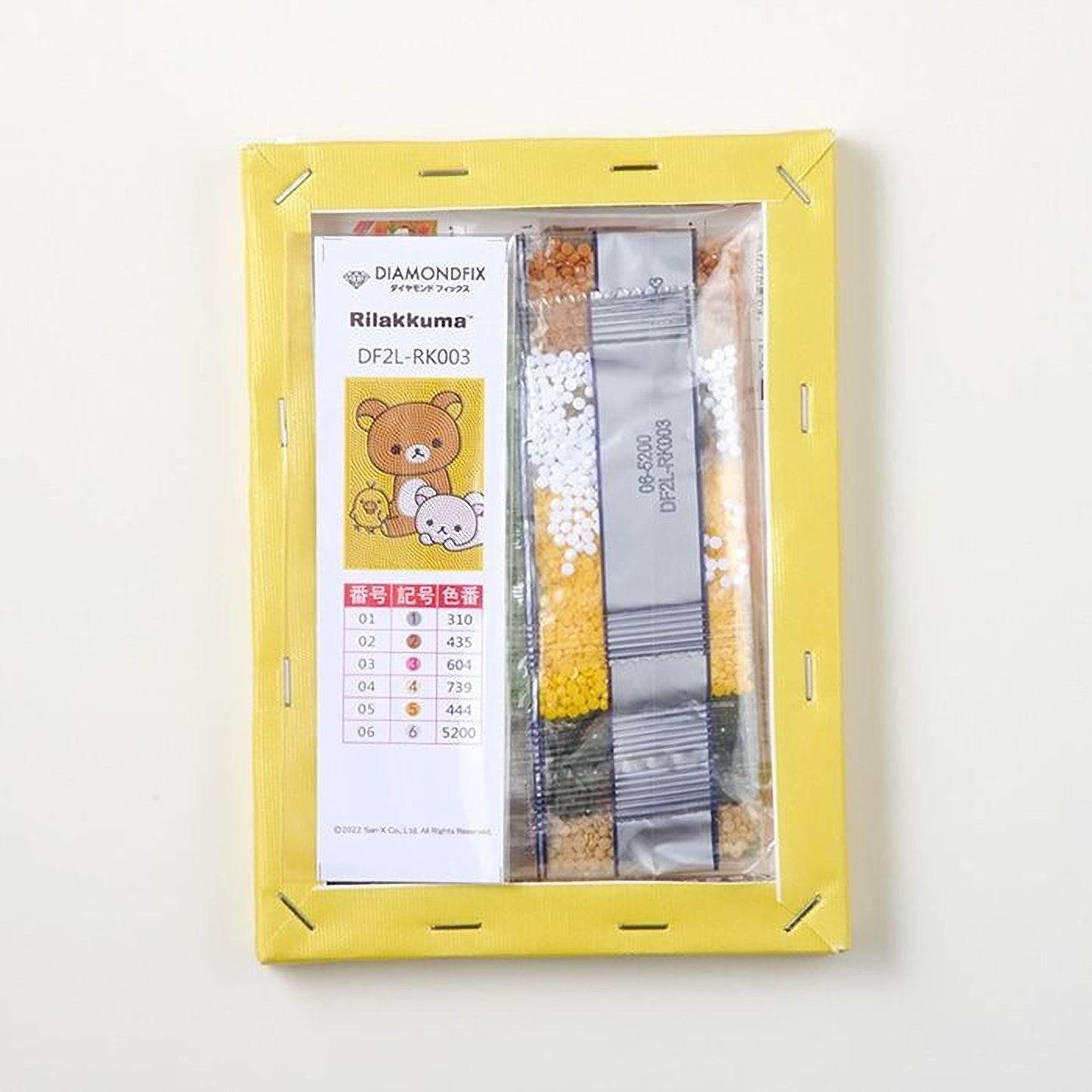 a yellow frame with a label and a clear plastic bag containing colorful beads or grains, possibly for a craft or art project.