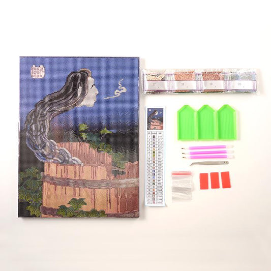 a painting of a woman's face, a diamond craft kit, and various craft supplies arranged on a white background.