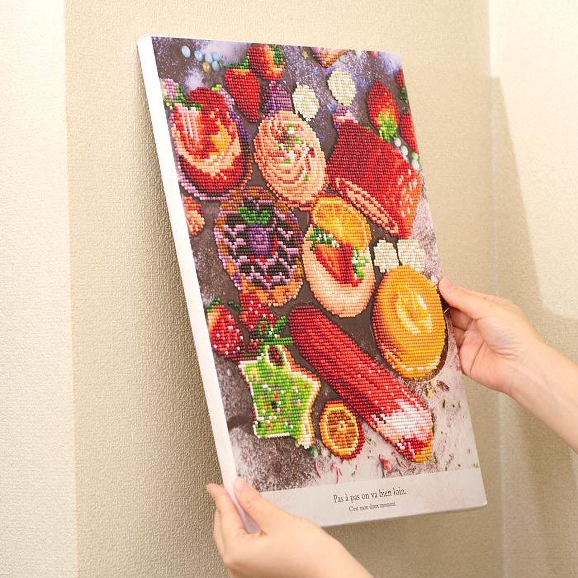 A person's hands are holding a framed collage of various colorful and artistic images, including desserts and other food items.