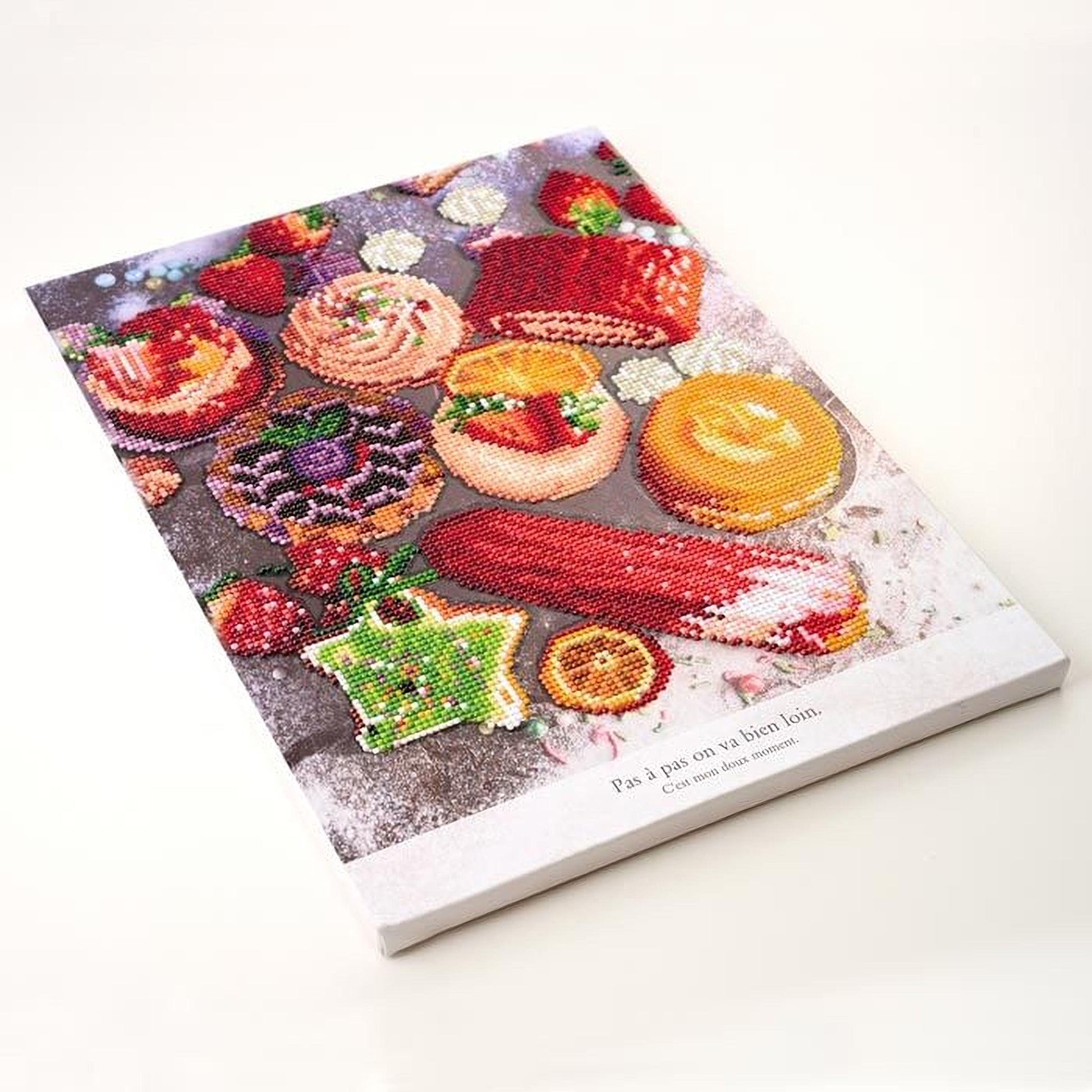 The image is a vibrant and colorful embroidered or needlepoint design depicting various desserts and pastries, including cakes, donuts, and fruit.