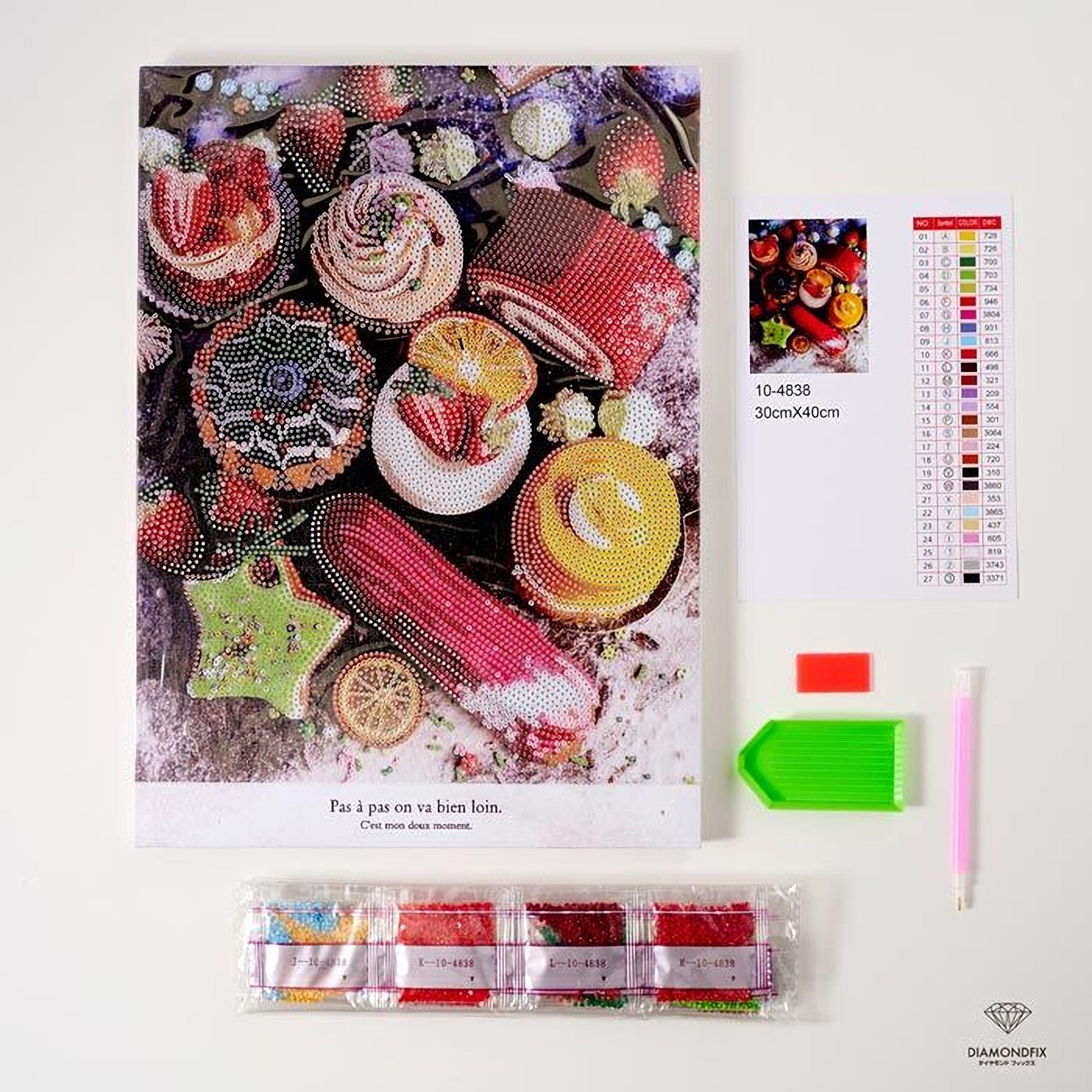 various items related to a DIY project, including a large poster with a colorful image of food items, a color chart, a diamond-encrusted pen, and a set of diamond-encrusted tools.