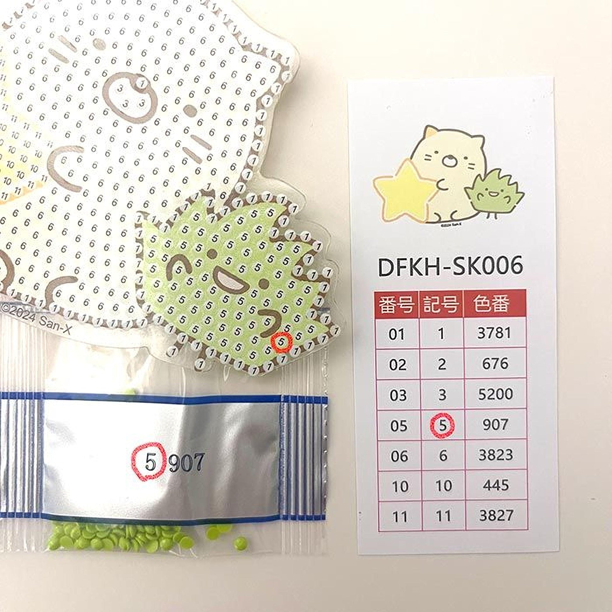 a collection of items, including a sticker with a cartoon cat, a price list, and a bag of green beads.