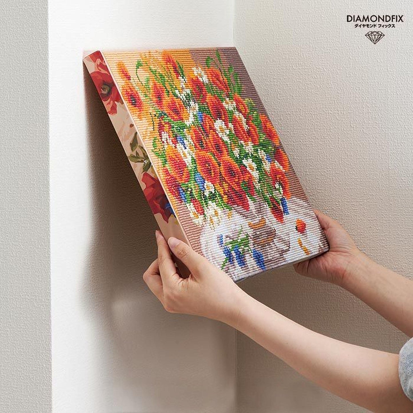 A person is holding a colorful canvas featuring a floral arrangement, which appears to be a painting or artwork.
