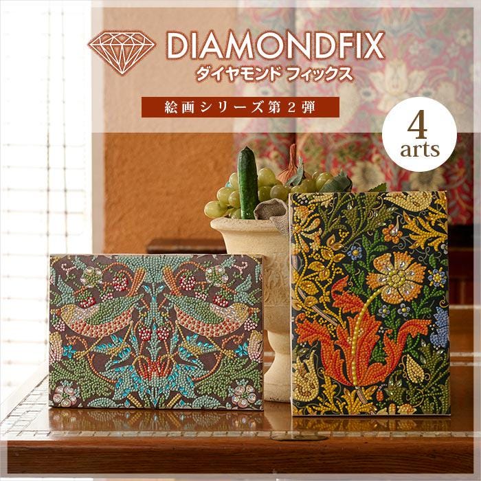 two framed artworks with intricate floral designs, displayed on a wooden surface. The artworks are placed next to a vase filled with green plants, creating a visually appealing and harmonious composition.