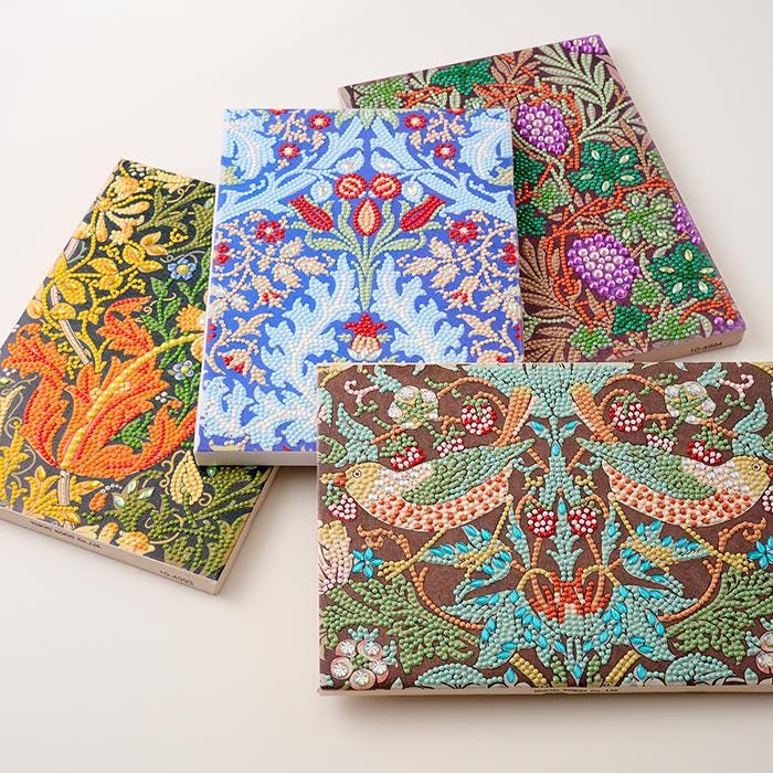 four notebooks with different floral and nature-inspired designs, including vibrant colors and intricate patterns.