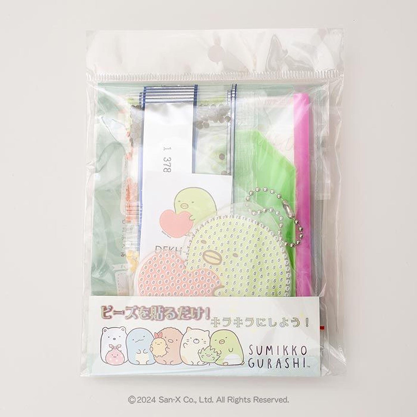 A package containing a variety of items, including a pink pen, a green and white polka dot object, and a small green and white polka dot object. The package also includes a label with Japanese text and illustrations of the same polka dot objects.