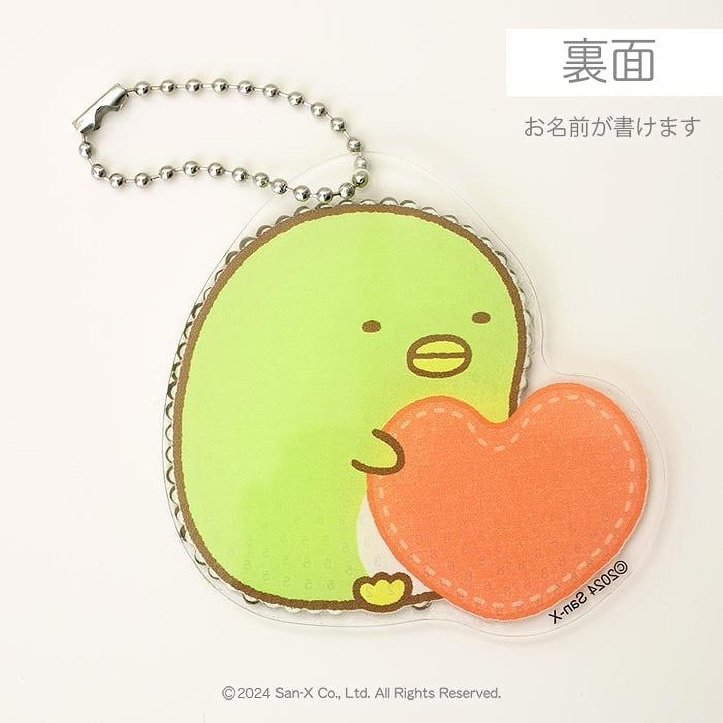A keychain with a green penguin holding an orange heart-shaped object.