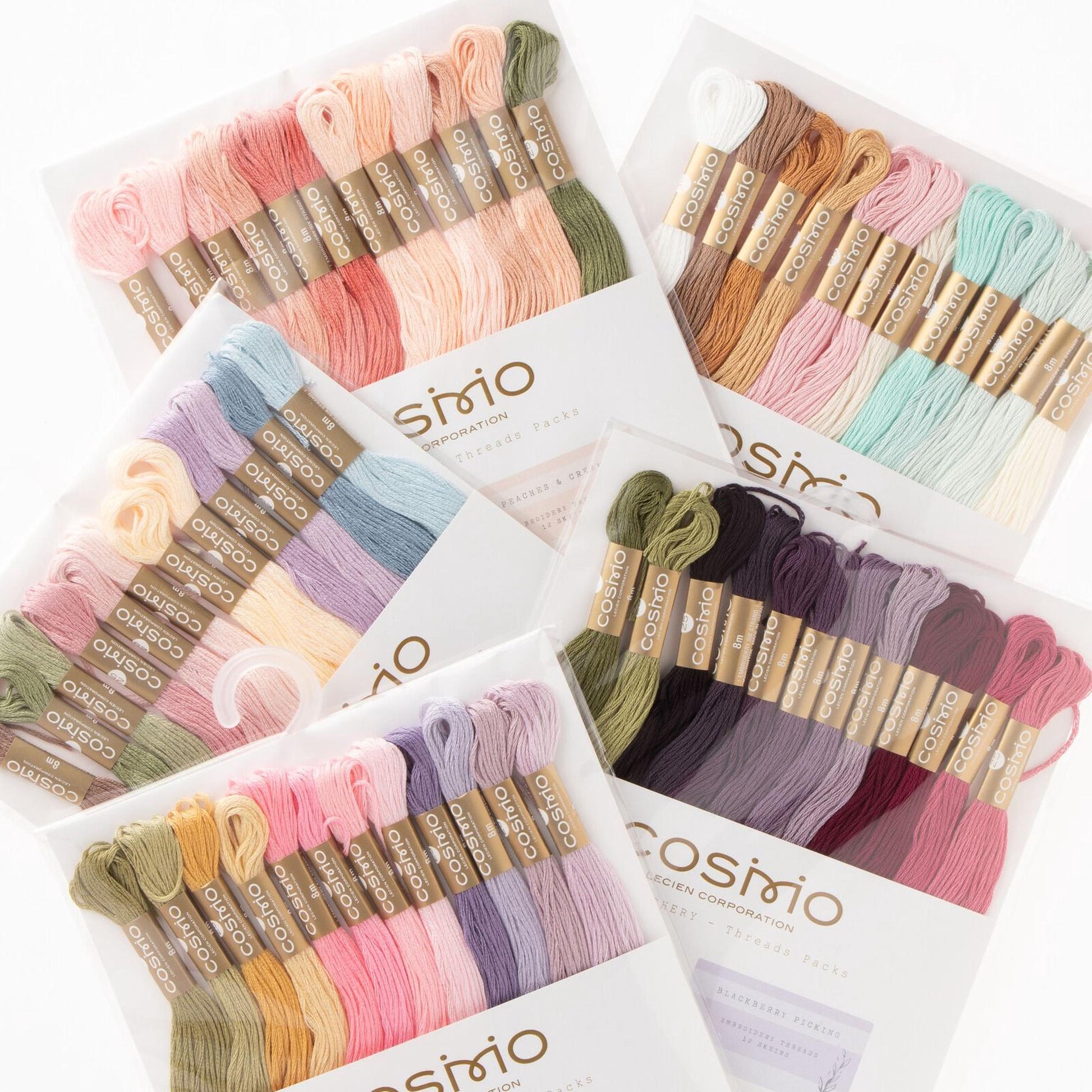 a collection of colorful spools of thread in various shades, including pink, blue, green, and purple, arranged in multiple packages.