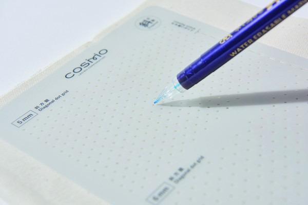 A blue pen is resting on a white surface, with the pen's tip pointing towards the top right corner of the image.