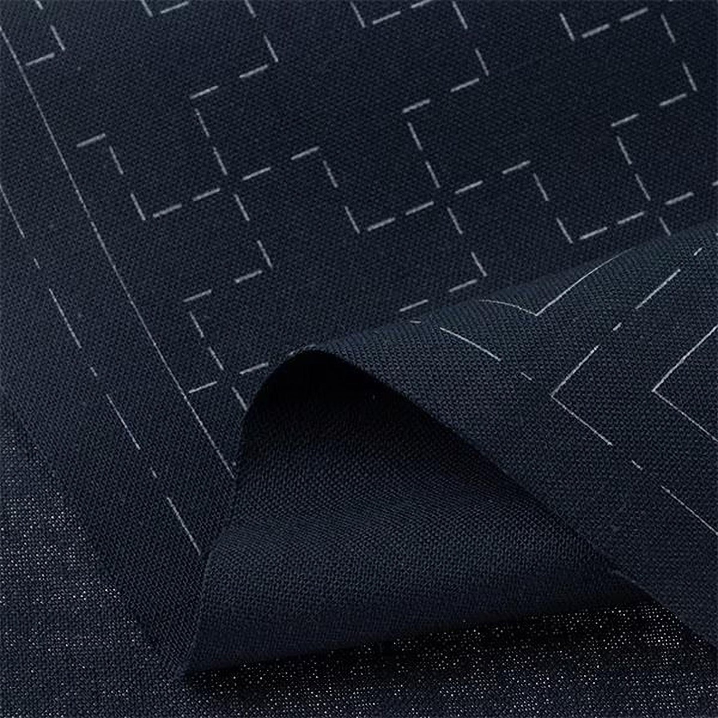 a close-up view of a dark fabric with a geometric pattern, featuring white lines and shapes.