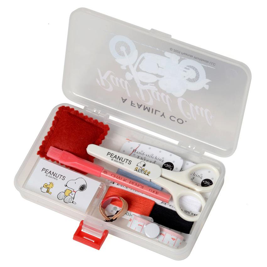 A clear plastic container filled with various sewing and crafting supplies, including scissors, a red brush, and other tools.