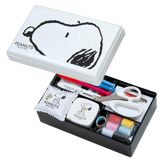 A Peanuts themed box containing various Peanuts-related items such as a Snoopy drawing, scissors, pens, and sewing supplies.