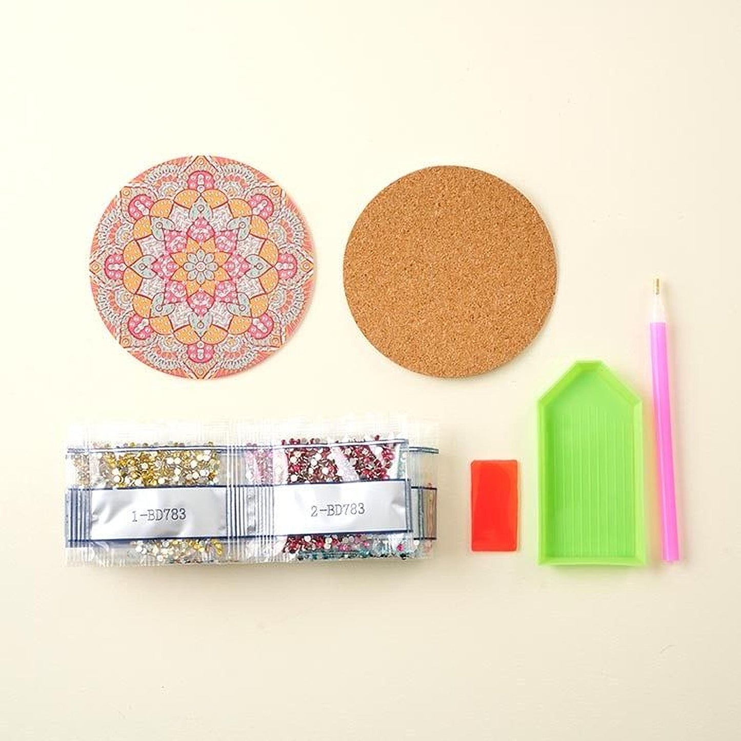 various craft supplies, including a cork coaster, a pen, a magnifying glass, a bead package, and a diamond tool.