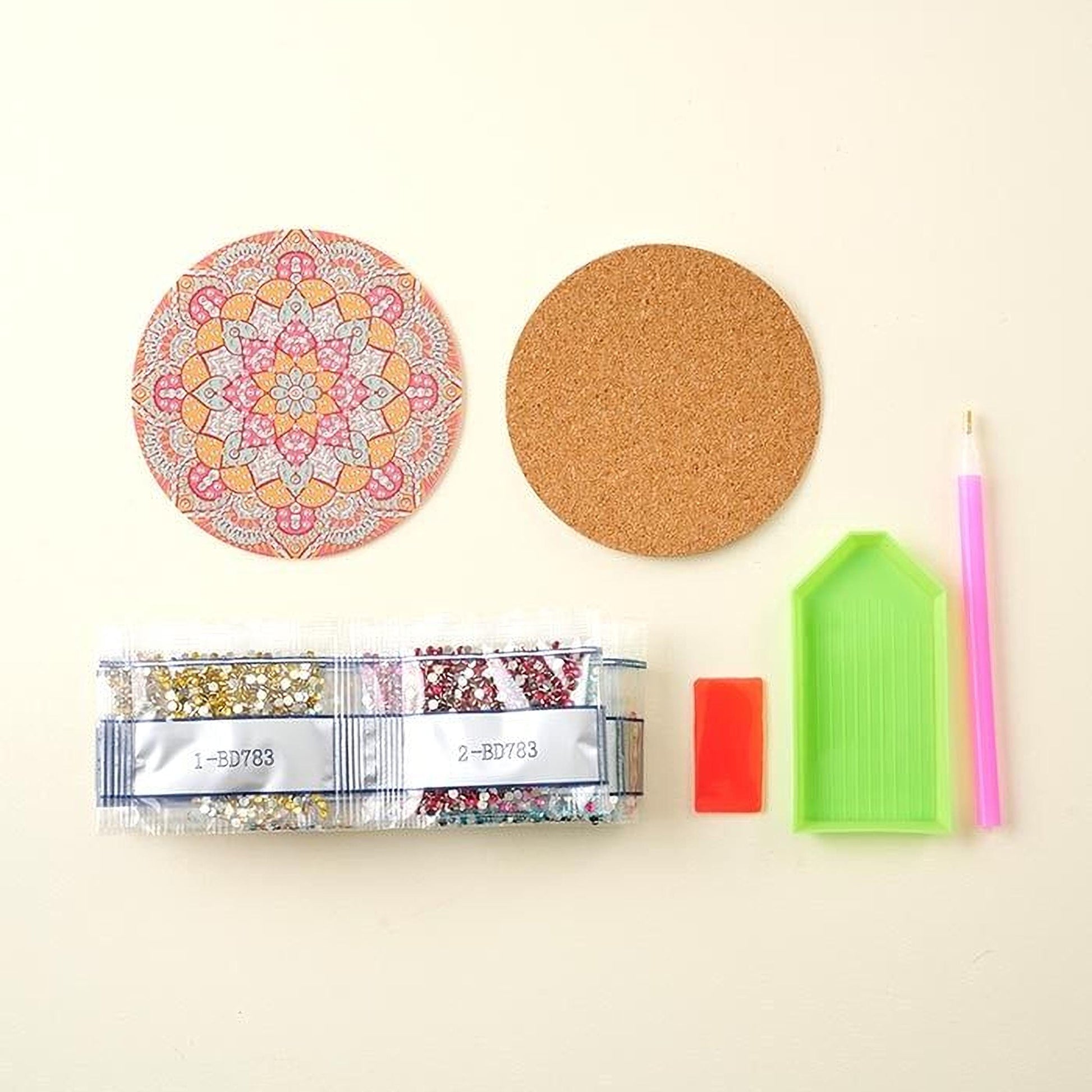 various craft supplies, including a cork coaster, a pen, a magnifying glass, a bead package, and a diamond tool.