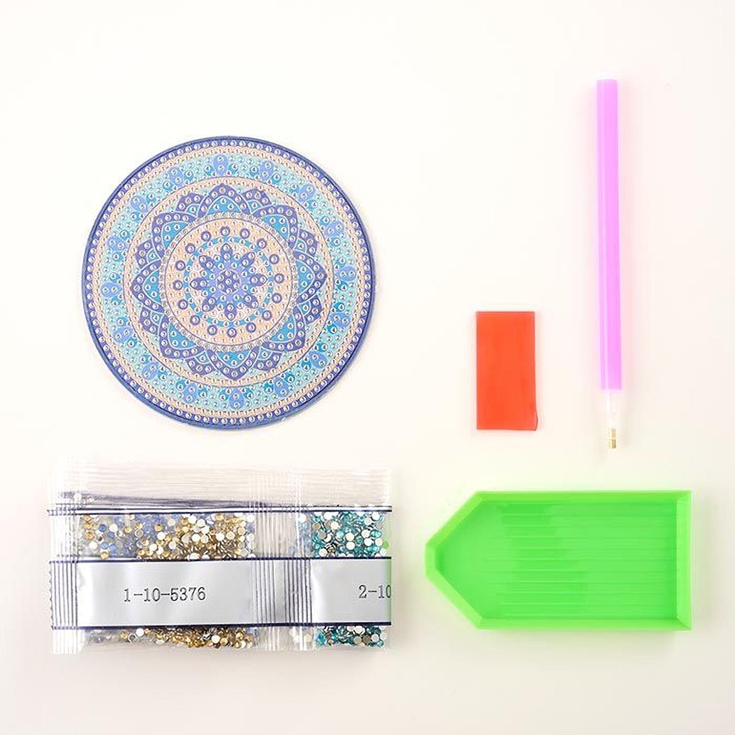 various craft supplies, including a decorative blue and gold plate, a green and orange pen, a clear plastic bag with glitter, a red and orange pencil, and a green and orange plastic tray.