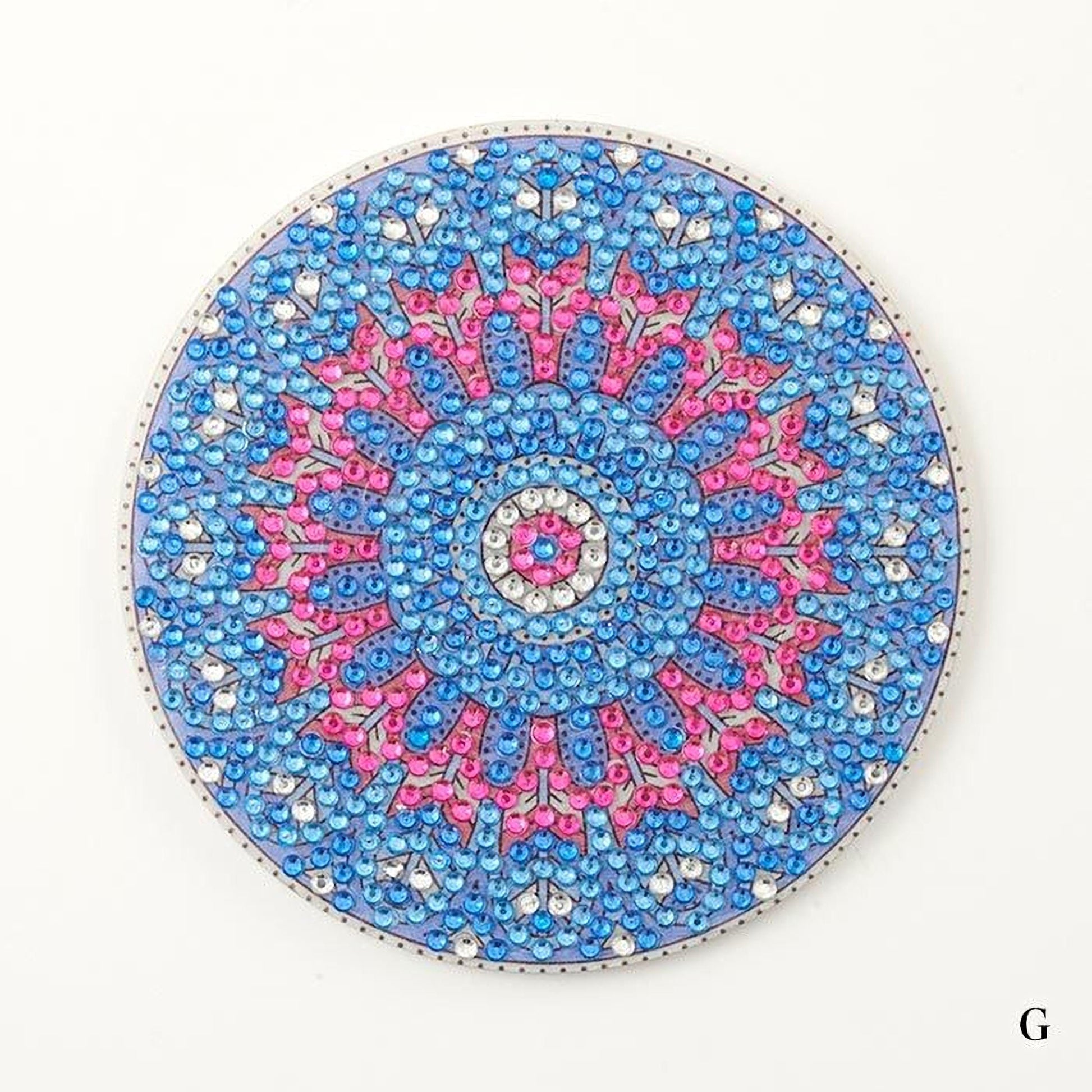 A round, ornate piece of jewelry or decorative item with a vibrant, colorful design featuring blue, pink, and silver elements.