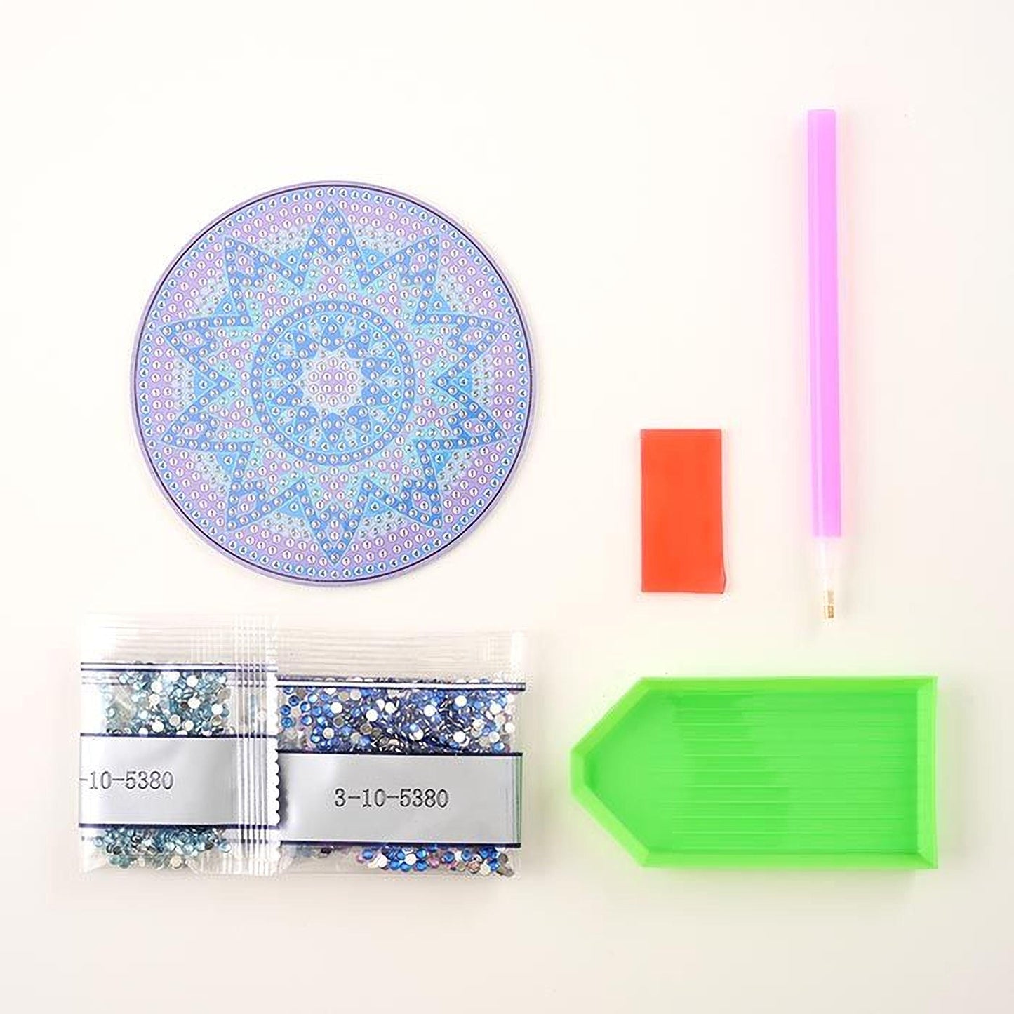 various craft supplies, including a pen, a pen holder, a magnifying glass, a green tray, and two bags of glitter beads.