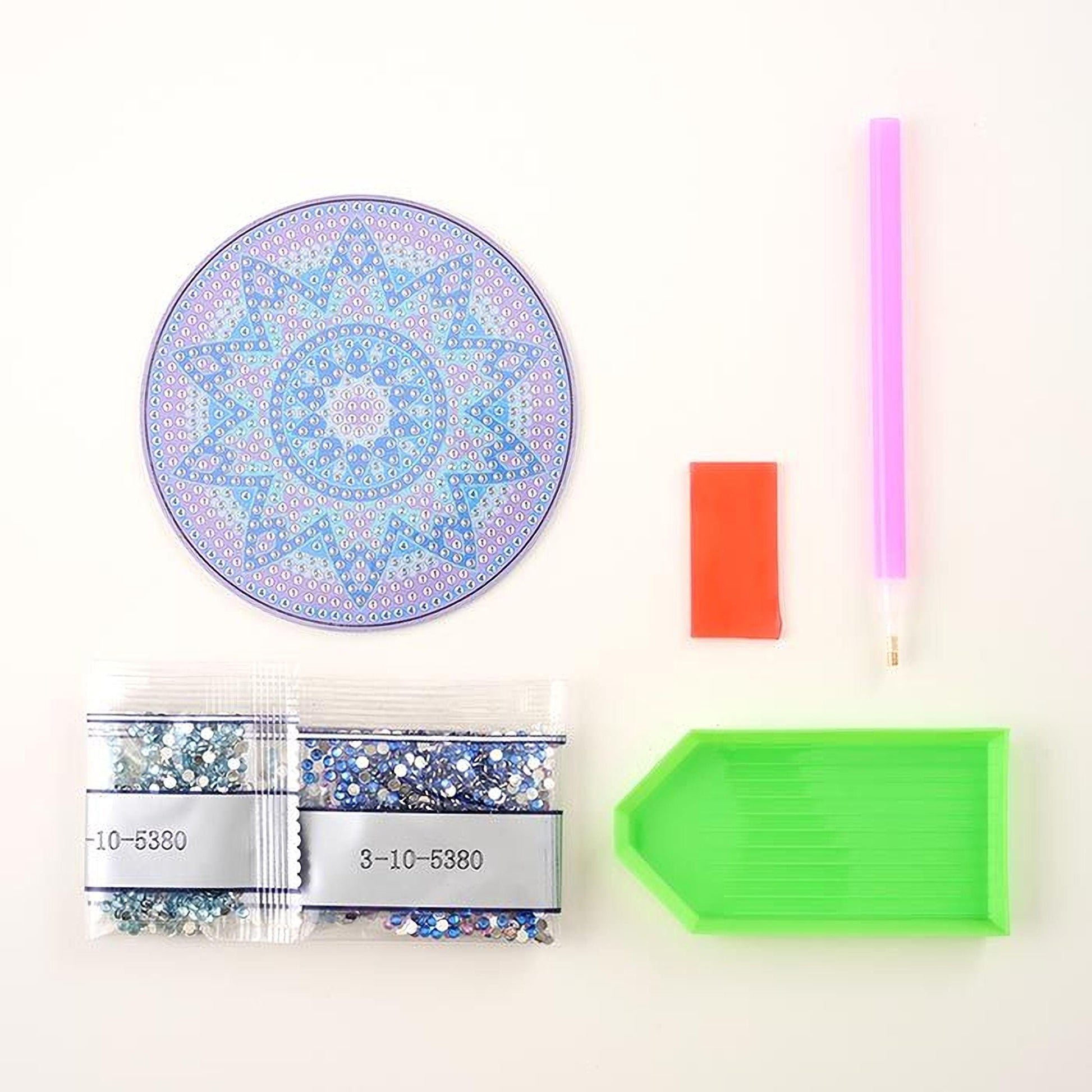 various craft supplies, including a pen, a pen holder, a magnifying glass, a green tray, and two bags of glitter beads.