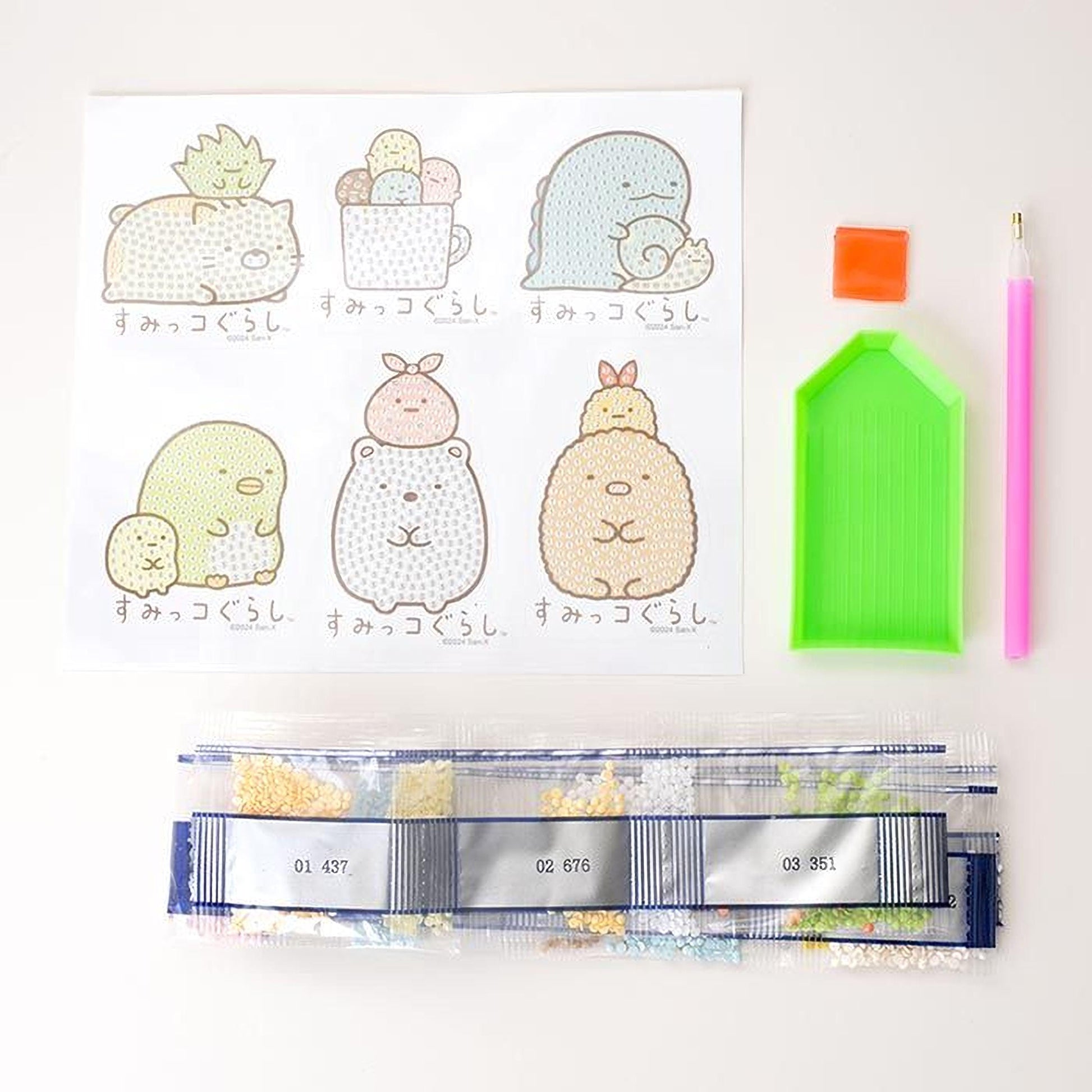 various craft supplies, including a pen, a green diamond plate, and a bag of colorful beads. There are also illustrations of cute animals, such as a cat, a dog, and a bird, along with some text in Japanese.