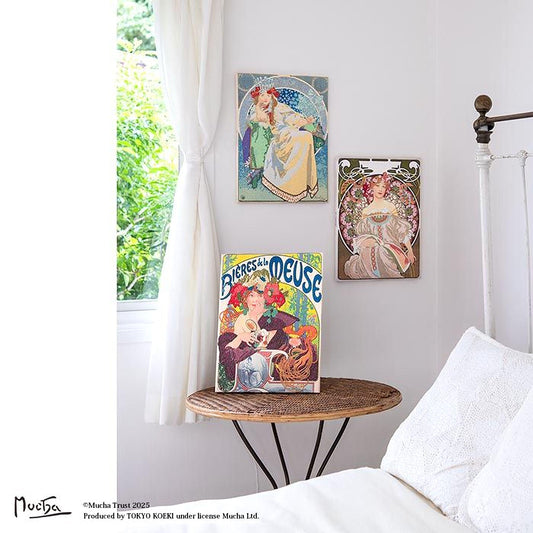 a bedroom with a bed, a table, and three framed artworks hanging on the wall.