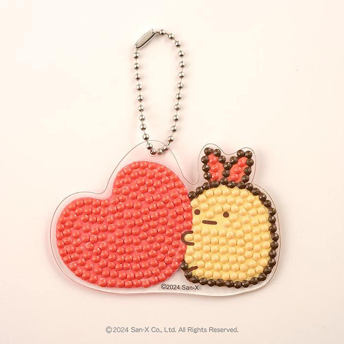 A heart-shaped pendant charm with a small yellow and brown insect figure attached to it, both made of small beads or dots.