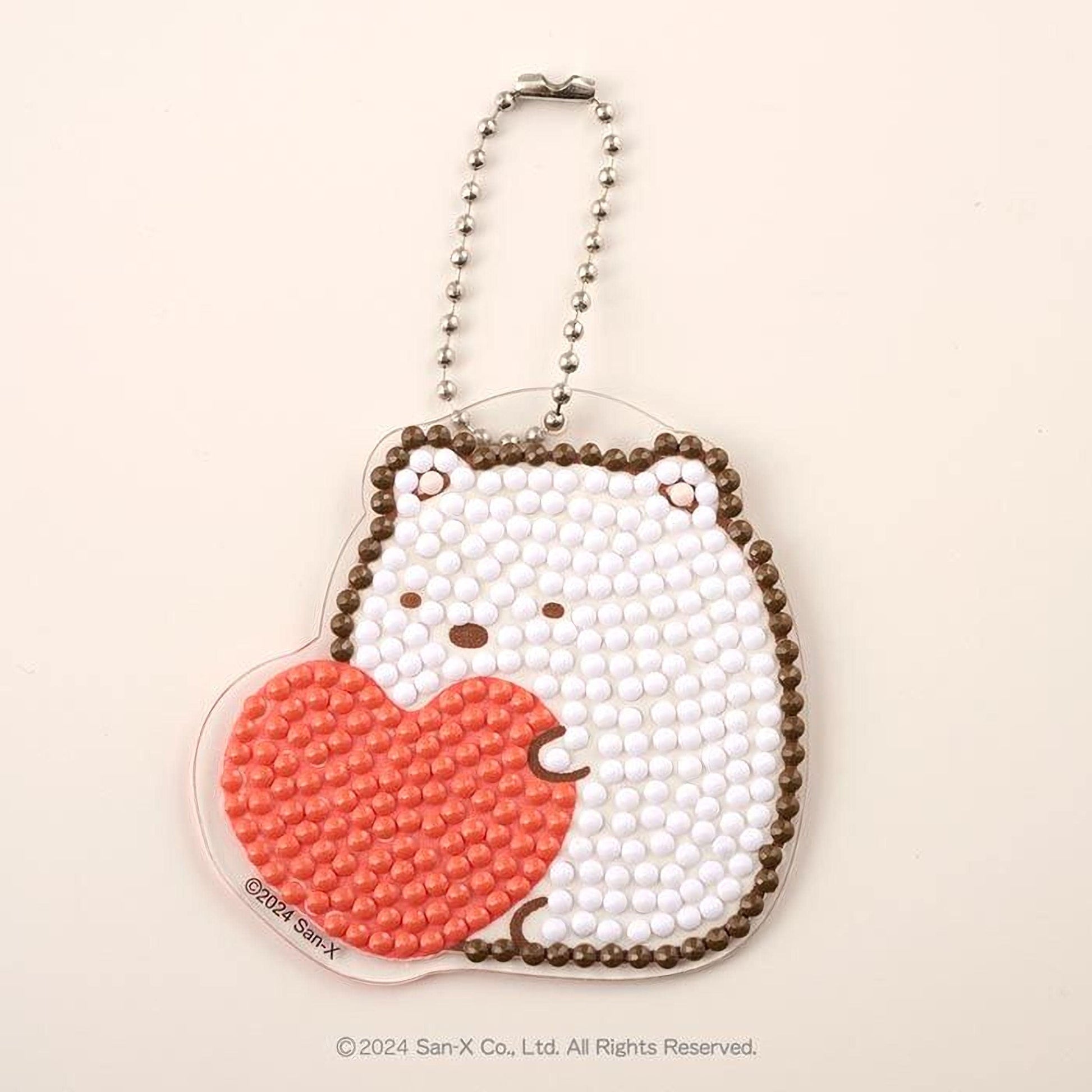 A heart-shaped pendant with a bear design, made of small white and orange beads.