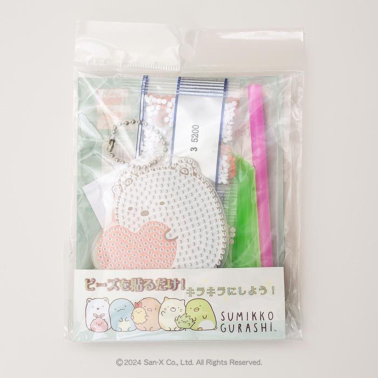 a package with a clear plastic bag, which appears to be a gift or a product. The package contains various items, including a keychain, a pen, and a toothbrush. The packaging also features a label with Japanese text and a cartoon character.
